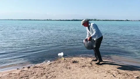 Collects important garbage in blue water of lake, cleaning nature Stock Footage 281558073