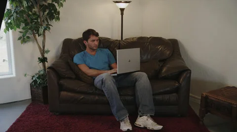 College Guy on Laptop Sitting on Sofa Stock Footage 35295611