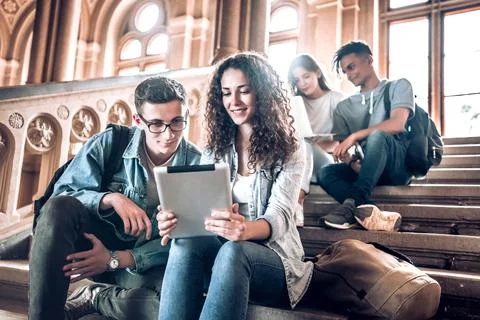 College life.Group of students using a tablet while sitting on stairs in univ Stock Photos