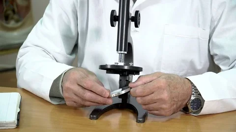 A college professor adjusting the mirror of microscope in the classroom Stock Footage 71999558