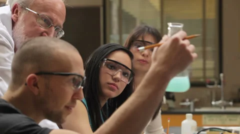 A college professor helps students understand a chemistry experiment Video stock 33881027