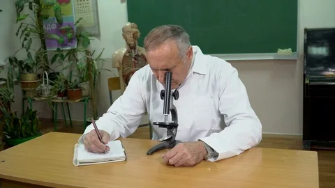A college professor working with microscope and taking notes in the classroom Stock Footage 71999828