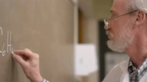 A college professor writes equations on the chalkboard Stock Footage 33877751