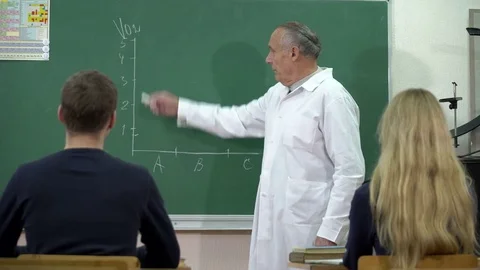 A college professor writes new topic on blackboard for his students Stock Footage 71985946