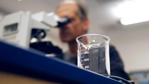 A college science professor looking through a microscope at cancer cells Stock Footage 100997353