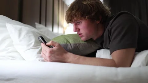 College student lying in bed late at night staring at smartphone screen showing  Stock Footage 318778770