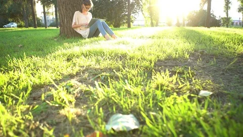 College student lying down on the grass and working on laptop, tracking shot Stock Footage 75628474