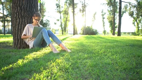 College student lying down on the grass and working on laptop, tracking shot Stock Footage 75628991