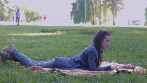 College student lying down on the grass and working on laptop Stock Footage 75851684
