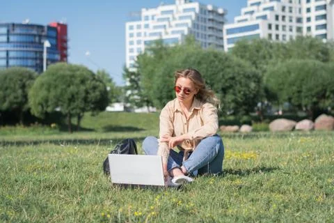 College student lying down on the grass working on laptop Stock Photos