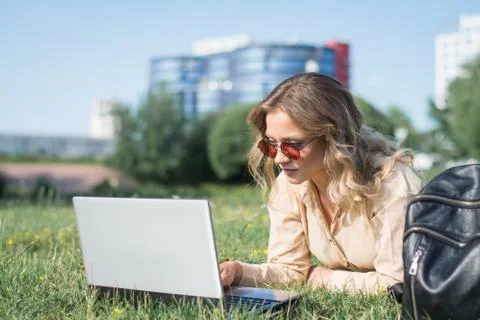 College student lying down on the grass working on laptop Stock Photos
