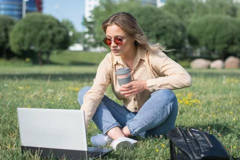 College student lying down on the grass working on laptop Foto stock