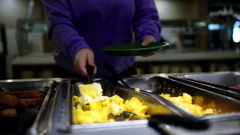 College Student Scoops Scrambled Eggs On Plate With Spoon In Cafeteria Stock Footage 172368141