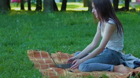 College student sits down on the plaid in the forest and working on 2 in 1 Stock Footage 75859663
