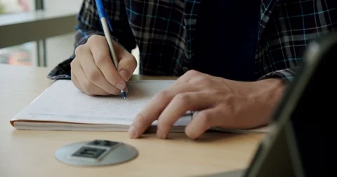 College student sitting in library, writes in a notebook, Close up Stock Footage 125958099
