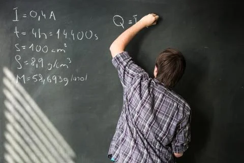 College student solving a math problem during math class in front of the blac Stock Photos