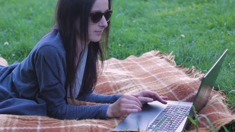 College student with sunglasses lying down on the plaid and working on laptop Stock Footage 75853086