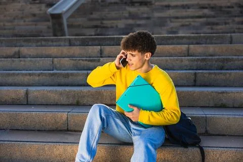 College student talking on smartphone while sitting on stairs Stock Photos
