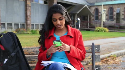 A college student texting on a bench on campus Stock Footage 43797548