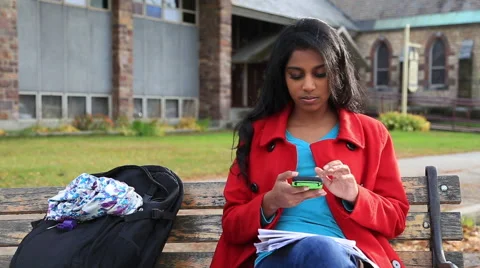 A college student texting on a bench on campus Stock Footage 43799000