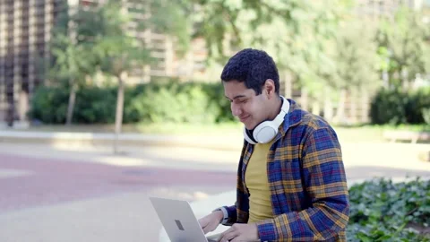 College student using laptop gesturing success sitting outdoors the campus Stock Footage 258326236