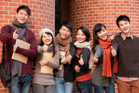 College students doing thumbs up in front of a university building Fotos Stock