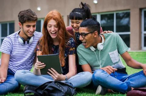 College students looking at digital tablet together Stock Photos