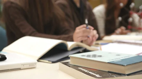 College students study course material in a group at a table filled with books Stock Footage 33878686