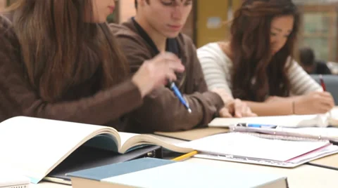 College students study course material in a group at a table filled with books Stock Footage 33878719
