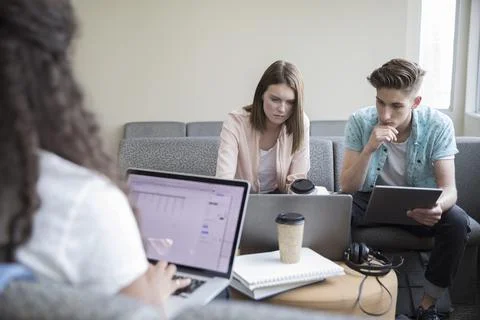 College students studying, using laptops and digital tablet in student lounge Stock Photos