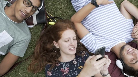 College students using smartphone and listening to music in campus Stock Footage 106342774