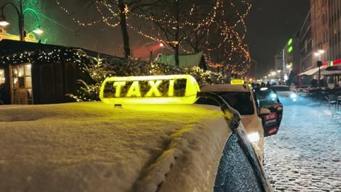 Cologne, Germany - Jan 05, 2025: Sign of taxi cab car is parked on a snowy st Stock Footage 300310021