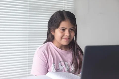 A Colombian Hispanic girl studying through a video call on a laptop at home,N Stock Photos