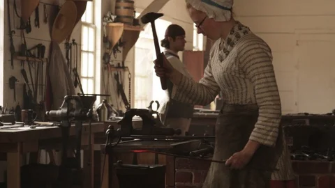 Colonial Blacksmiths Pounding Hot Iron with Antique Hammer - Recreation Stock Footage 106673339