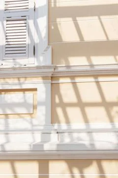 Colonial style facade with striped shadow. Stock Photos