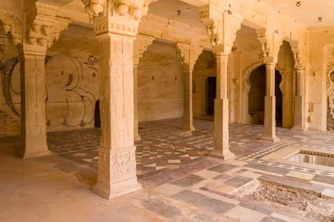 Colonnaded interior room with patterned floor and graffiti at Taragarh Fort in Stockfoto's