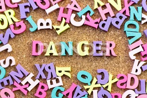 Color alphabet in word danger with another letter as frame on cork board back Stock Photos