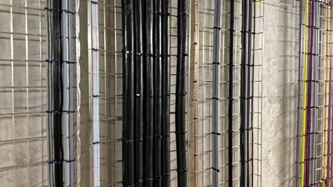 Color Coded Electrical Conduits on Concrete Wall in Data Facility Stock Footage 341544980