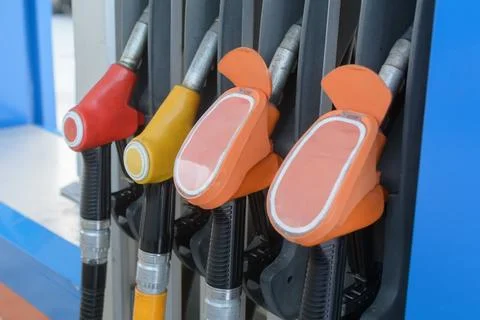 Color coded fuel nozzles rest in gas station dispenser, showing everyday ener Stock Photos