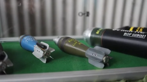 Color coded mortar rounds displayed behind glass on green felt with sharp fins a Stock-Footage 311150344
