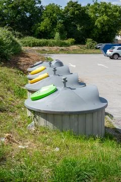 Color coded waste containers beside a parking area Stock Photos