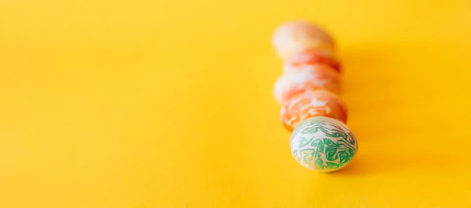 Color easter eggs differen patterns. Line of eggs on yellow background 库存照片