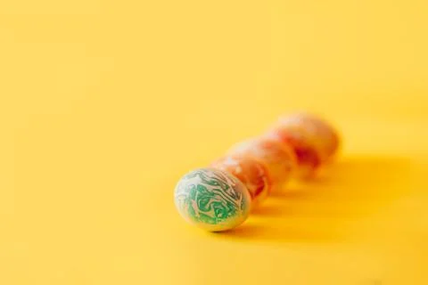 Color easter eggs differen patterns. Line of eggs on yellow background 库存照片