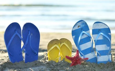 Color Flip flops on the sandy beach next to sea Stock Photos