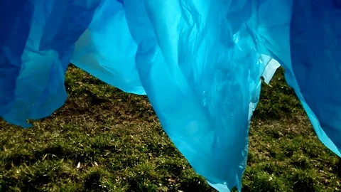 Color polythene on green grass background. Movement of polyethylene. Stock Footage 127982655
