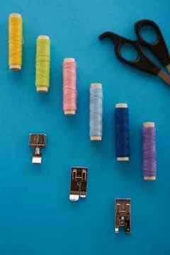 Color thread, scissors and sewing the elements on top of a blue background Stock Photos
