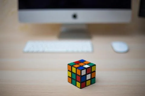 Colored 3D combination puzzle Rubik's cube three by three lies on a wooden ta Stock Photos