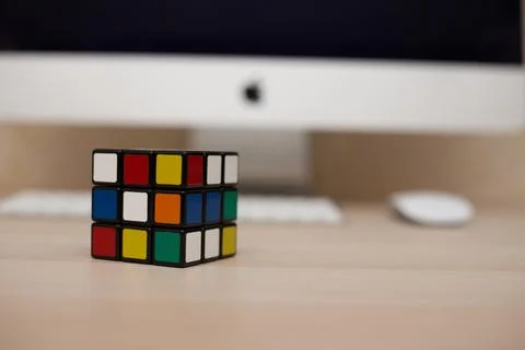 Colored 3D combination puzzle Rubik's cube three by three lies on a wooden ta Stock Photos