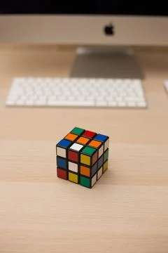 Colored 3D combination puzzle Rubik's cube three by three lies on a wooden ta Stock Photos