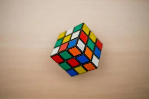Colored 3D combination puzzle Rubik's cube three by three lies on a wooden ta Stock Photos